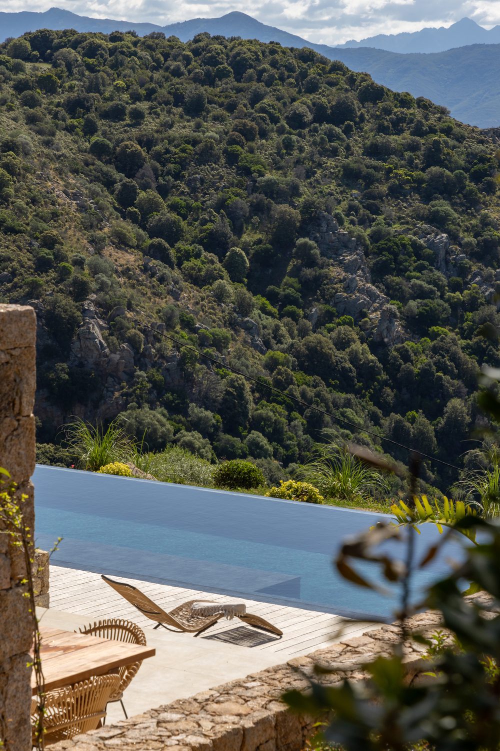 Vue aérienne d'une villa avec piscine et terrasse en pierre construite par Entasis Construction en Corse-du-Sud